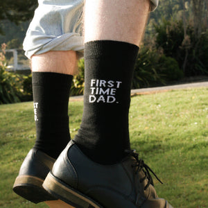 Person wearing First time Dad Crew Socks in black cotton with white text